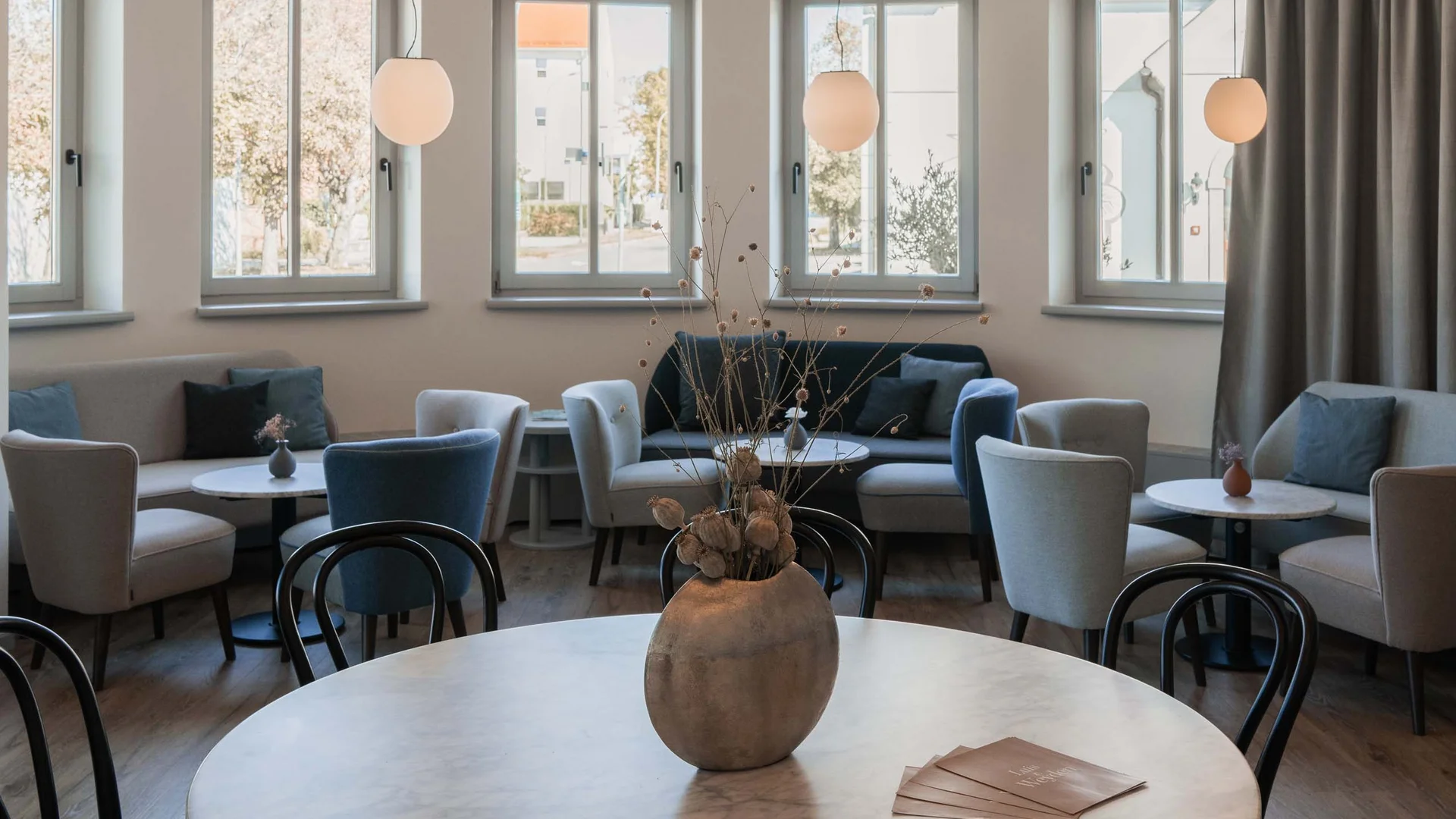 Luis von Weyden: der Treffpunkt in Weiden am See Modern eingerichteter Sitzbereich mit runden Tischen, Stühlen und großen Fenstern