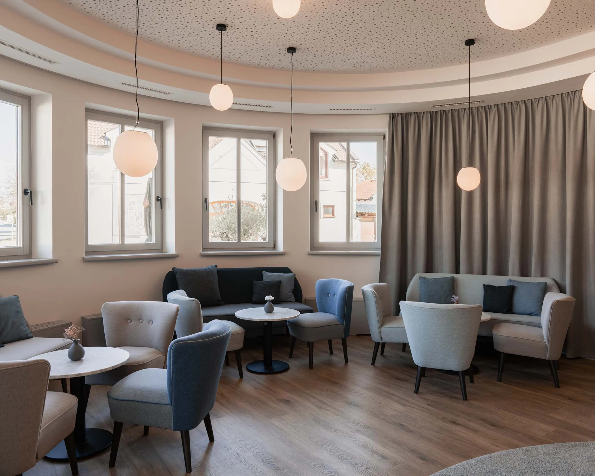 Impressionen aus dem Luis von Weyden Moderner Wartebereich mit Sesseln, Sofas und runden Tischen unter hängenden Lampen