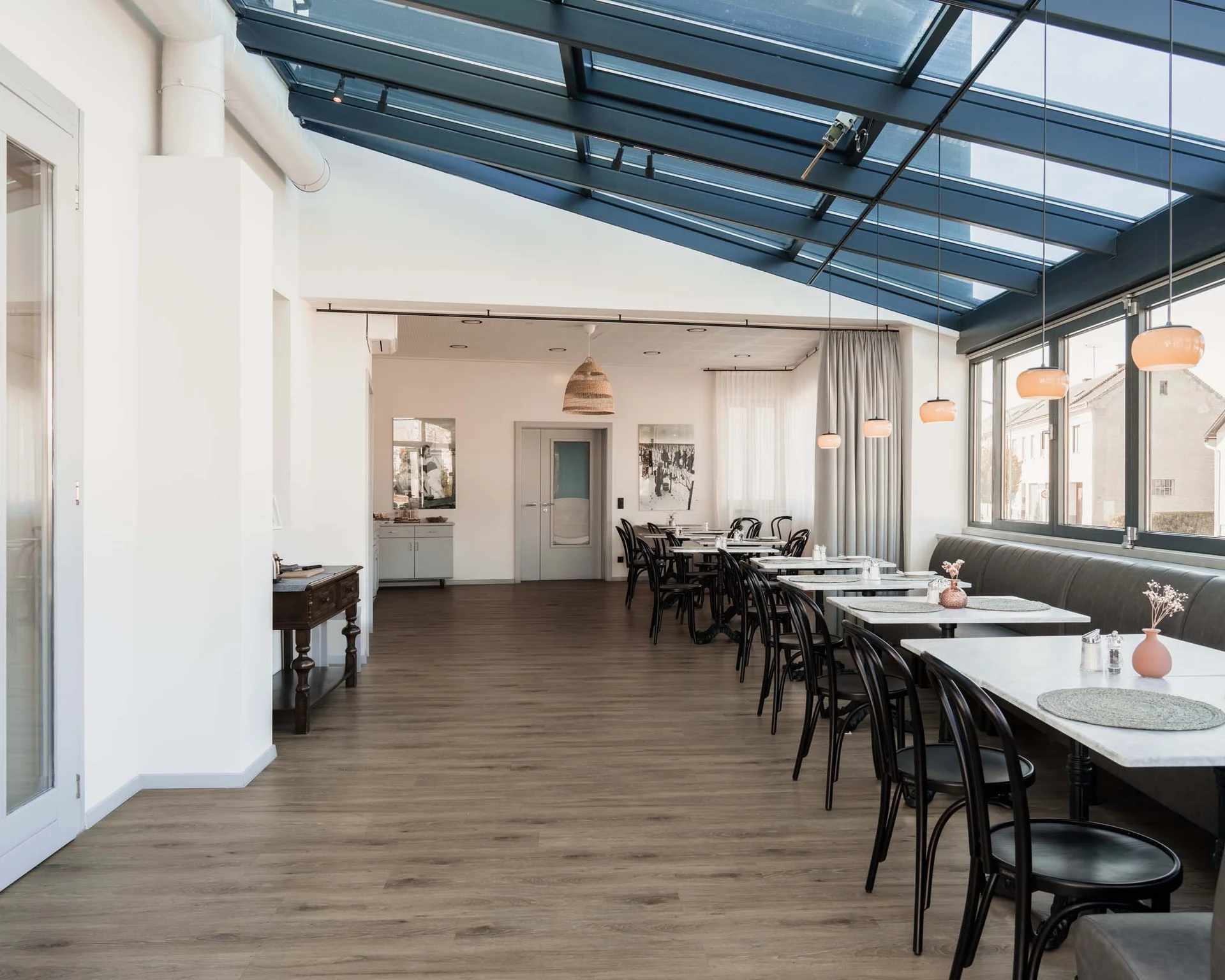 Impressionen aus dem Luis von Weyden Moderner heller Speiseraum mit Glasdach und Tischen an Fenstern