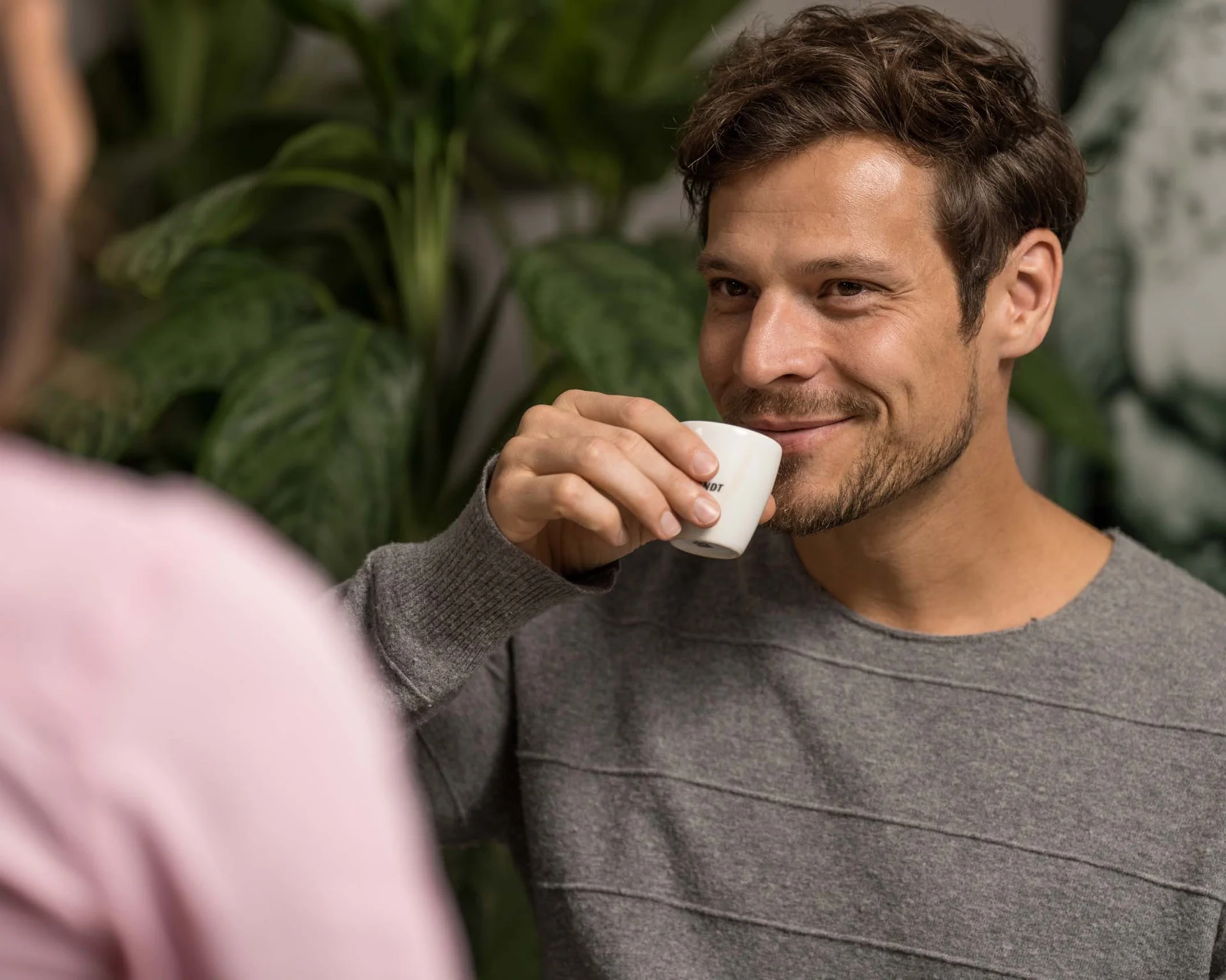 Impressionen aus dem Luis von Weyden Mann trinkt Kaffee und lächelt in einem grünen Raum