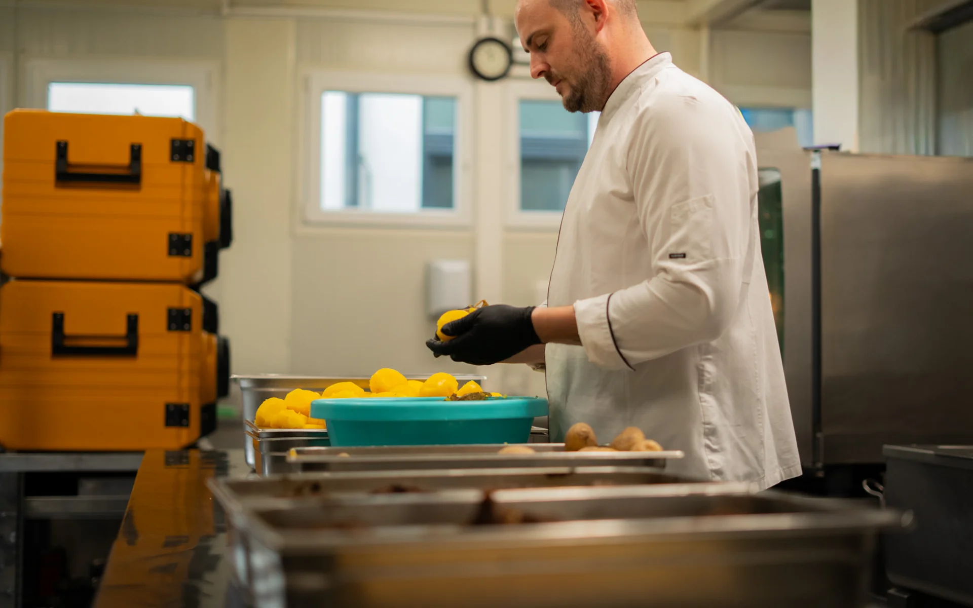 Luis von Weyden: Ihr Catering-Service in Weiden am See Koch schält gelbe Kartoffeln in einer Großküche