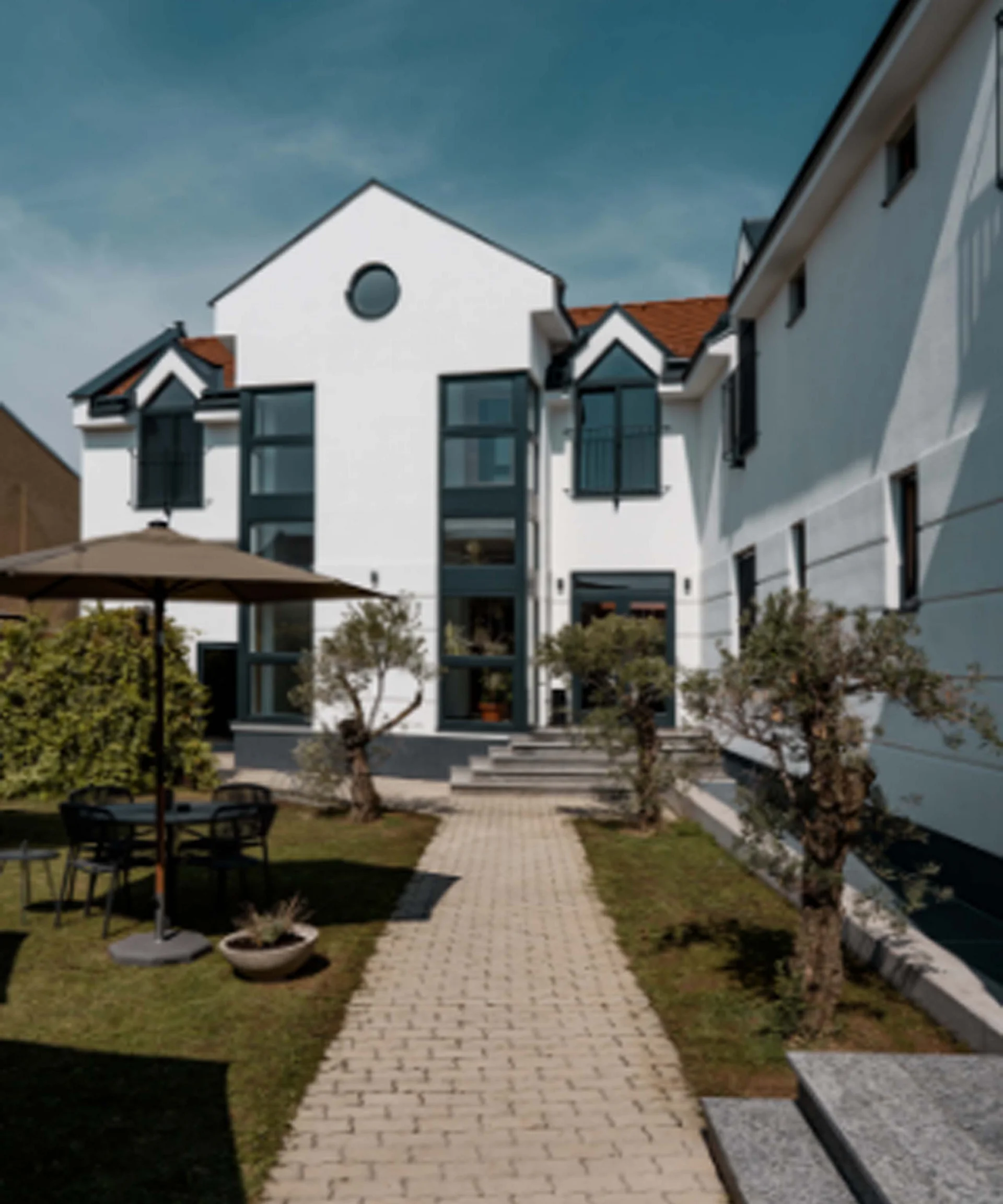 Luis von Weyden: der Treffpunkt in Weiden am See Weißes Mehrfamilienhaus mit Garten und Gartentisch mit Sonnenschirm