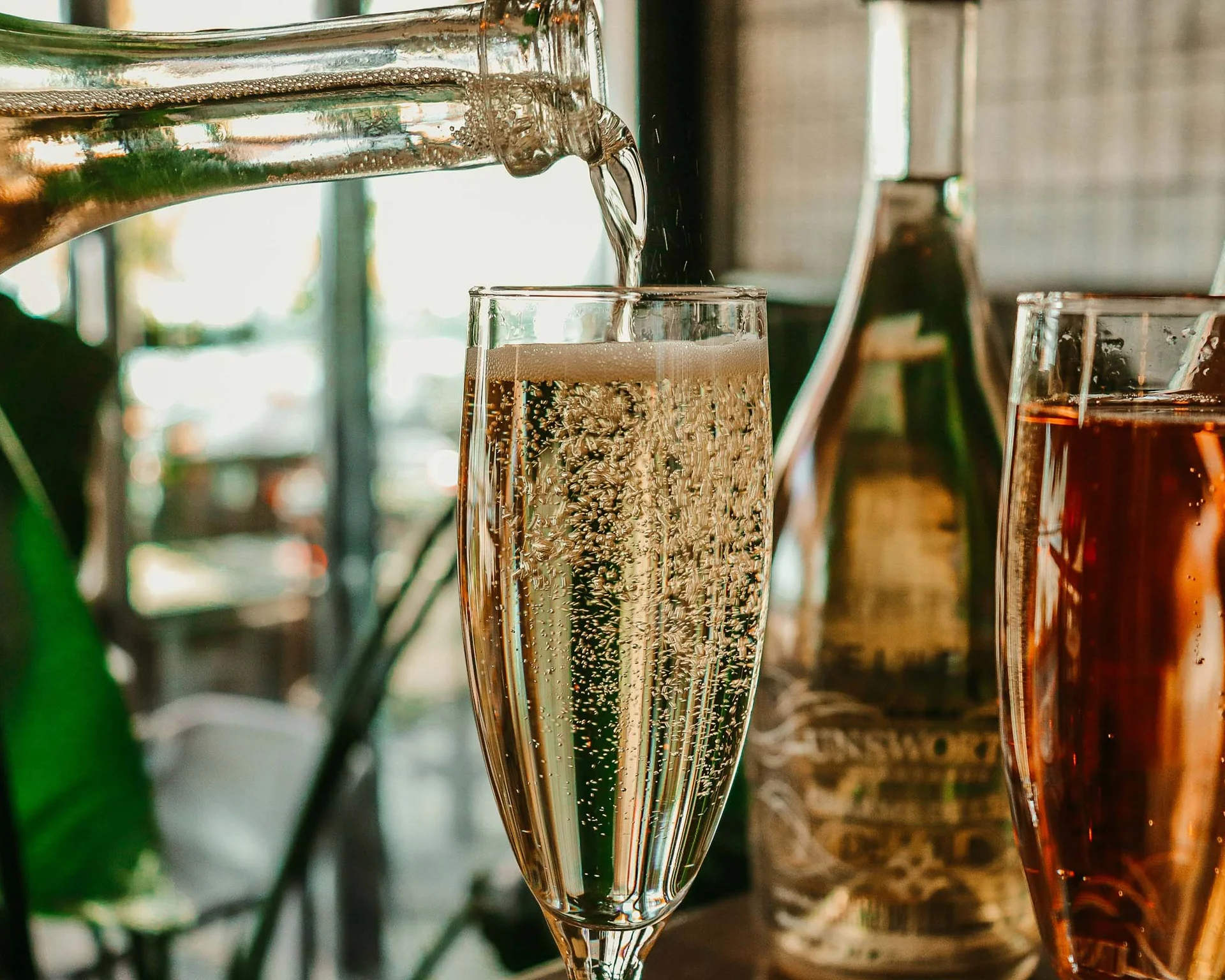 Impressionen aus dem Luis von Weyden Sekt wird in ein Glas eingeschenkt, mit anderen Flaschen im Hintergrund