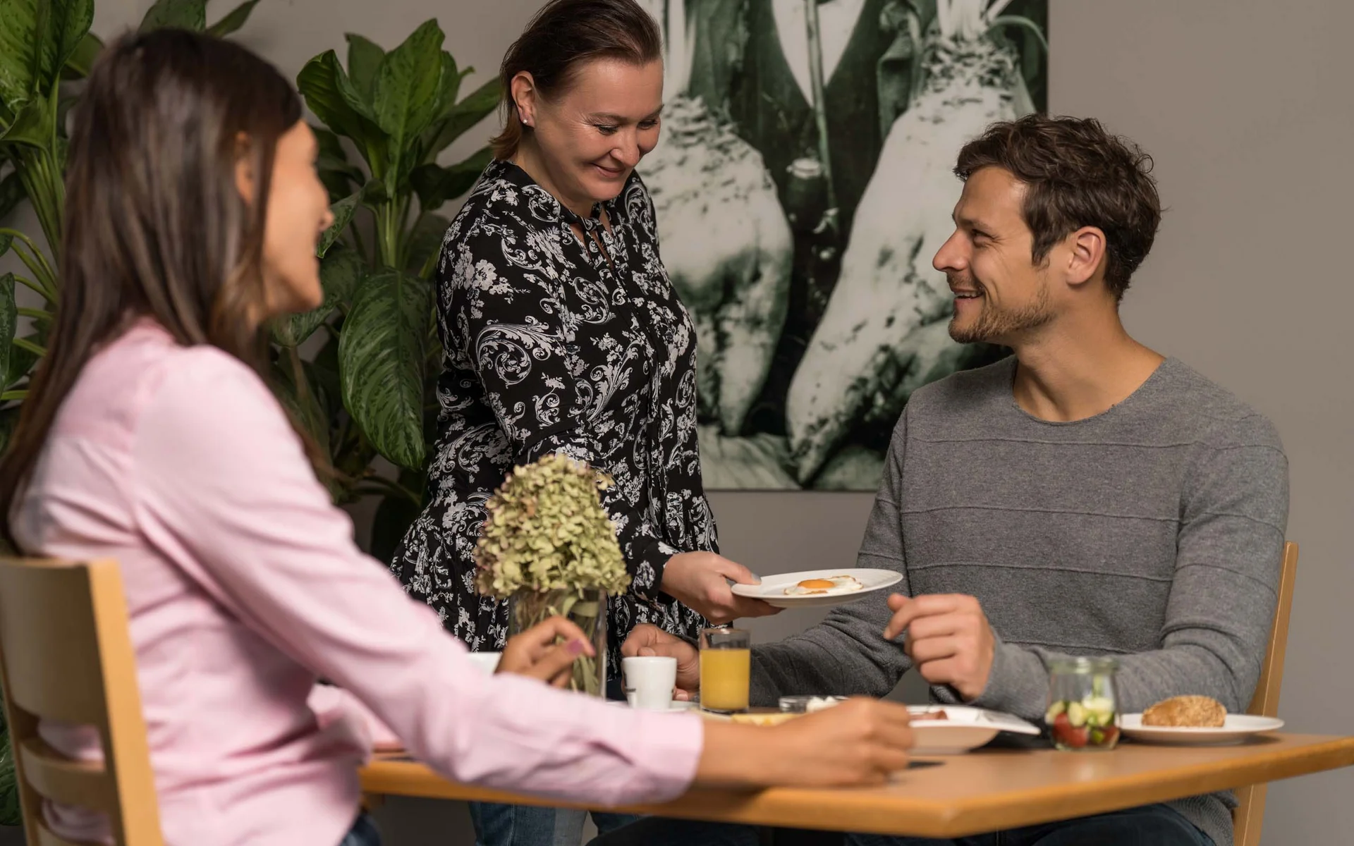 Luis von Weyden: Frühstück in Weiden am See Frau serviert Mann ein Frühstücksei an einem Tisch mit einer weiteren Frau