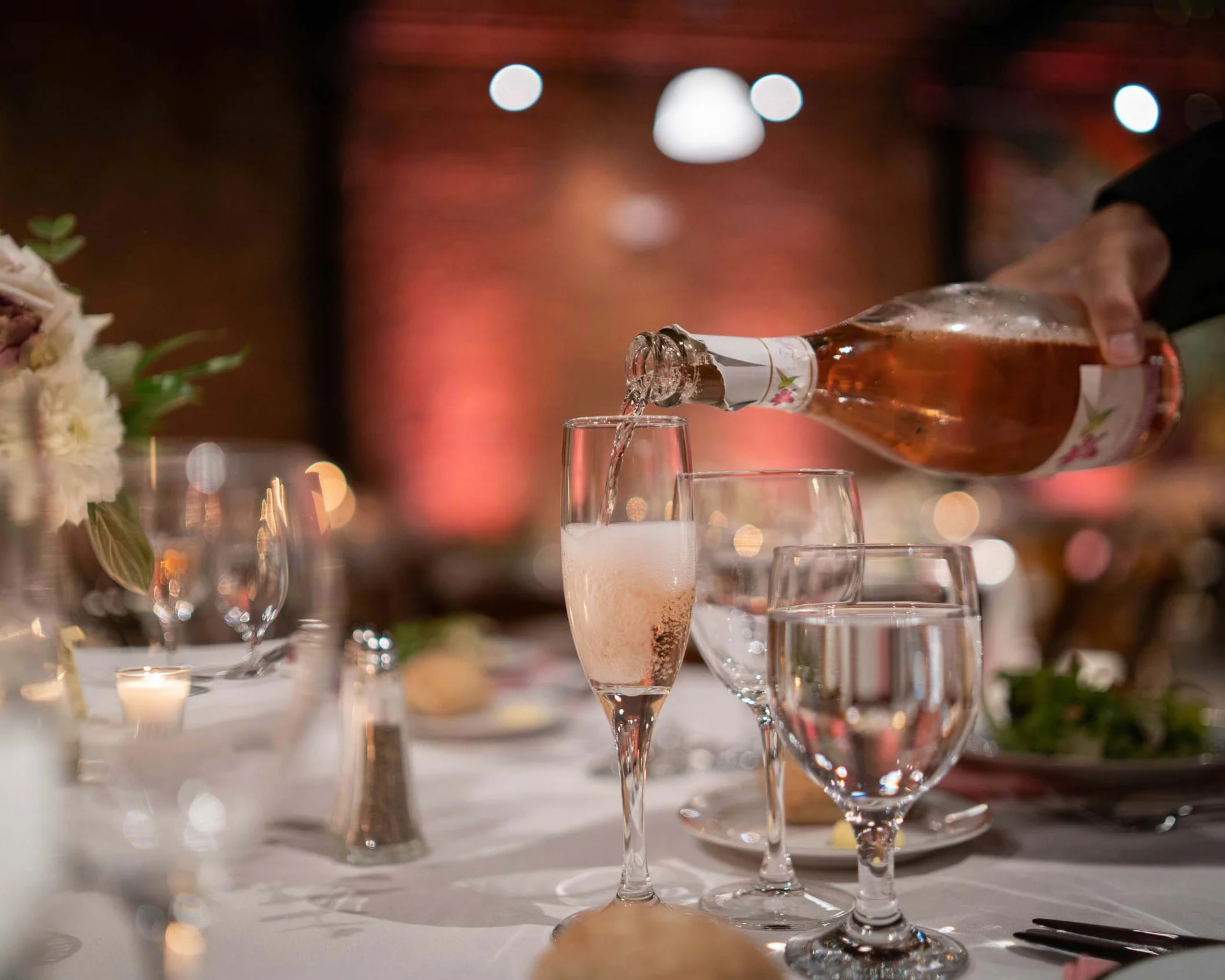 Impressionen aus dem Luis von Weyden Sektflasche gießt in ein Sektglas bei einem festlich gedeckten Tisch