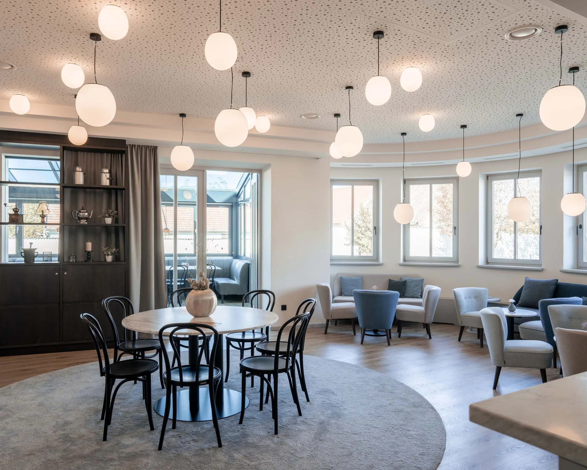 Impressionen aus dem Luis von Weyden Heller moderner Aufenthaltsraum mit runden Tischen und ovalen Hängelampen