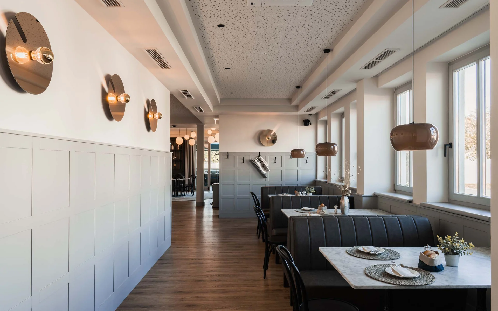 Luis von Weyden: Frühstück in Weiden am See Modernes Restaurant mit Sitzbänken, Tischen und großen Fenstern