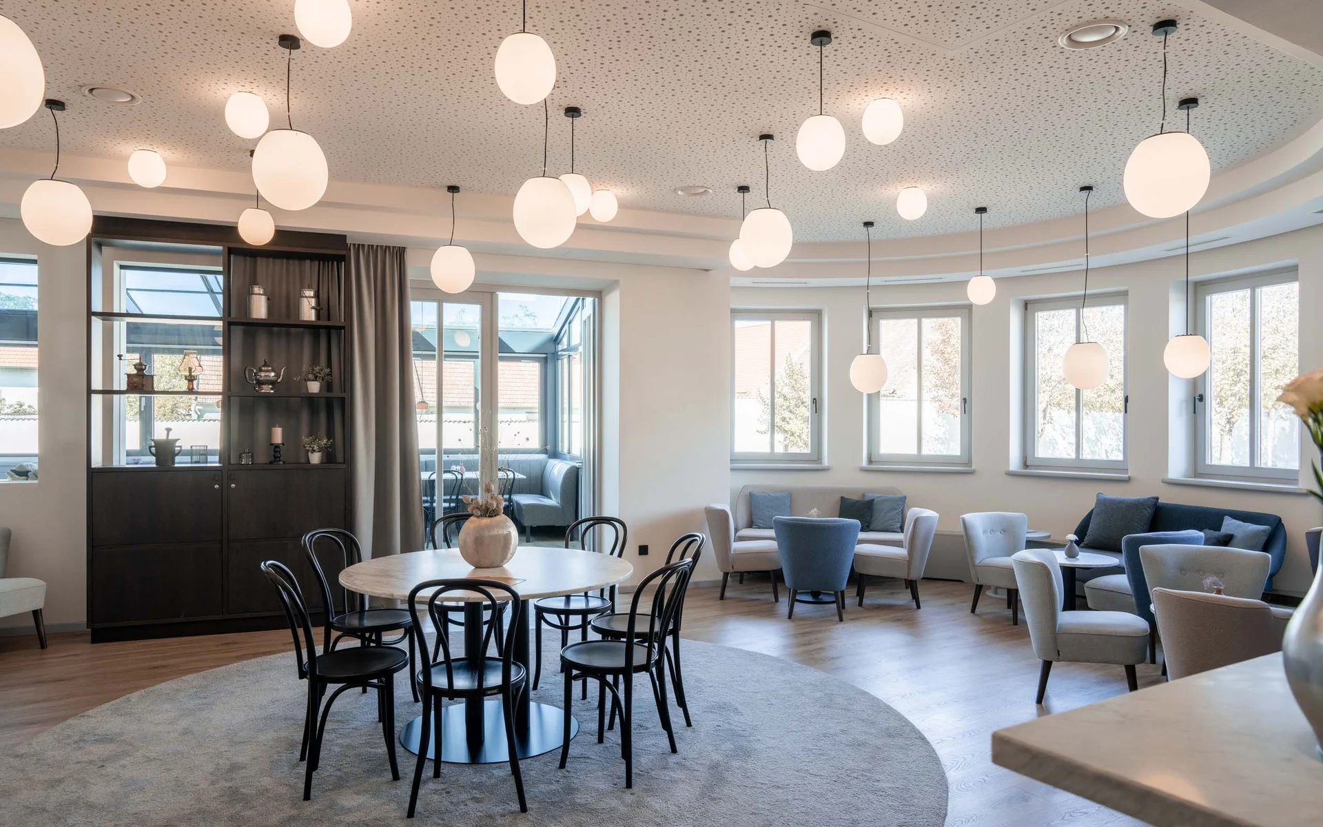 Luis von Weyden: die stylishe Pension in Weiden am See Heller moderner Aufenthaltsraum mit runden Tischen und ovalen Hängelampen